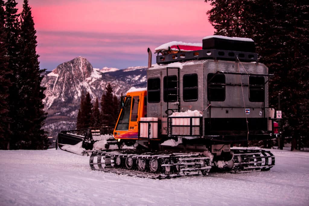 A snowcat on the slopes at sunset