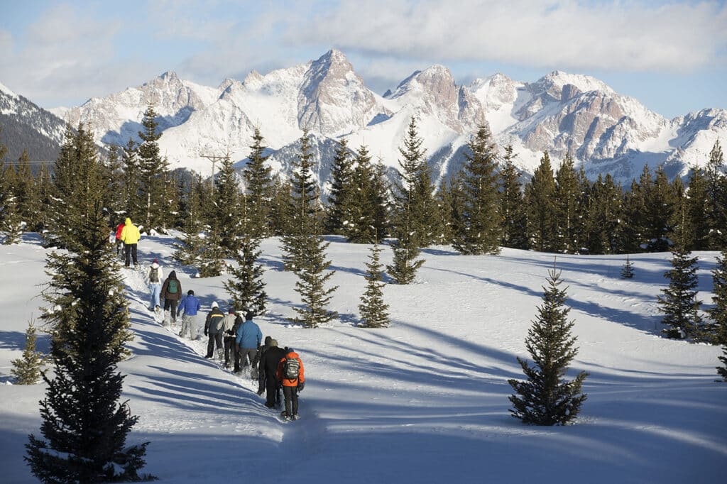 A snowshoe tour group walks towards the needles mountains