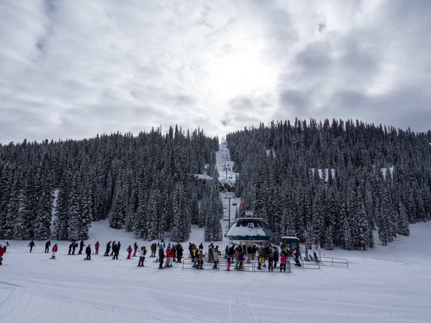 Skiers and snowboards wait to board lift 3