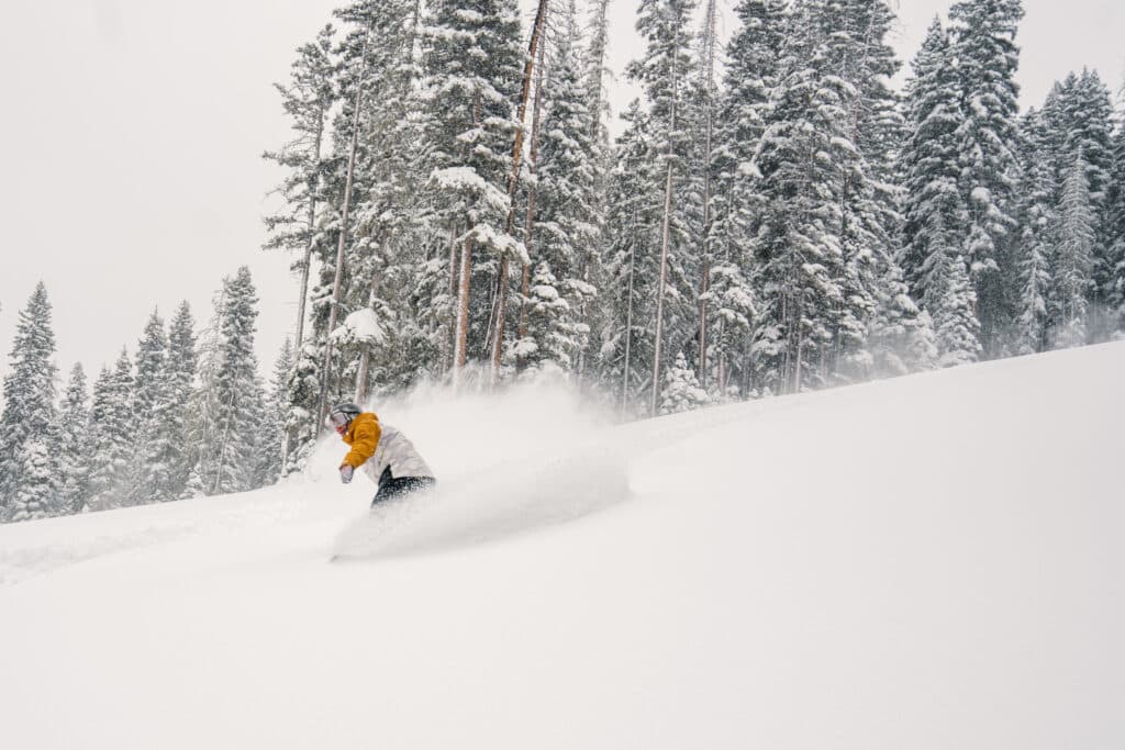 Snowboarder turning through knee deep powder