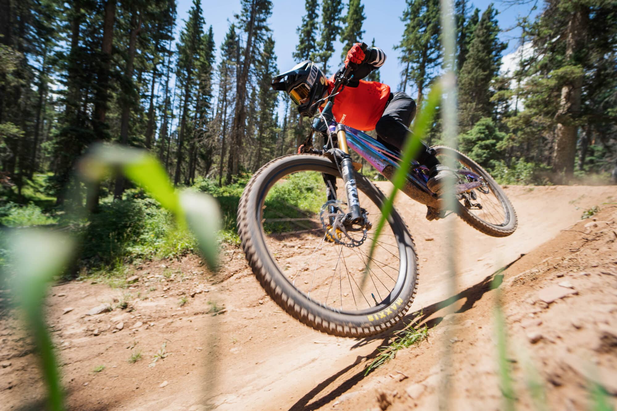 Mountain biker pins downhill turn captured through tall grass