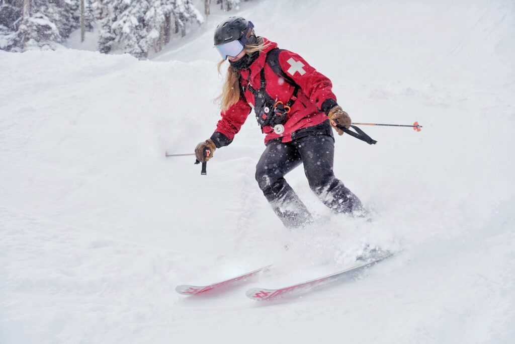 Female ski patroller skiing in powder