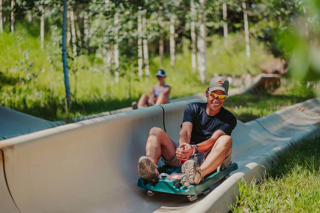 Adult rider smiles as he races down the alpine slide