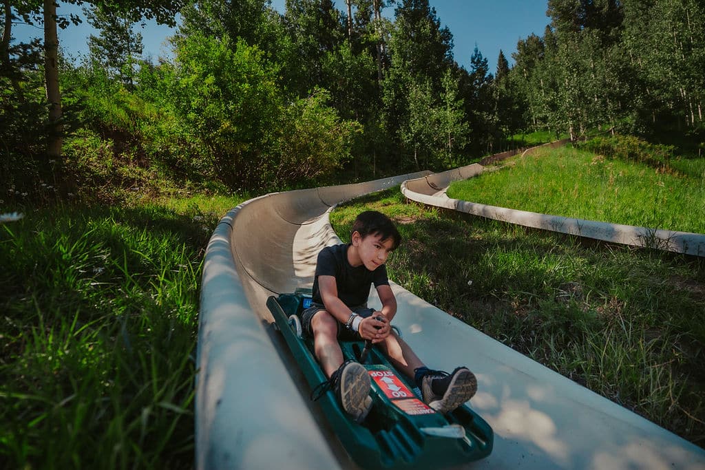 Young kid hyper focused as he pins a turn on the alpine slide