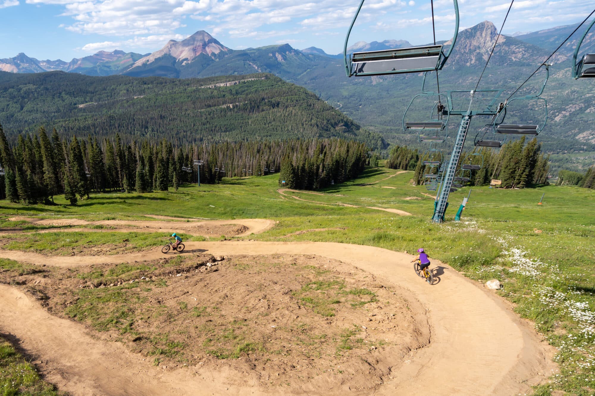 Female mountain bikers take on the wide bank turns of 7th Heaven