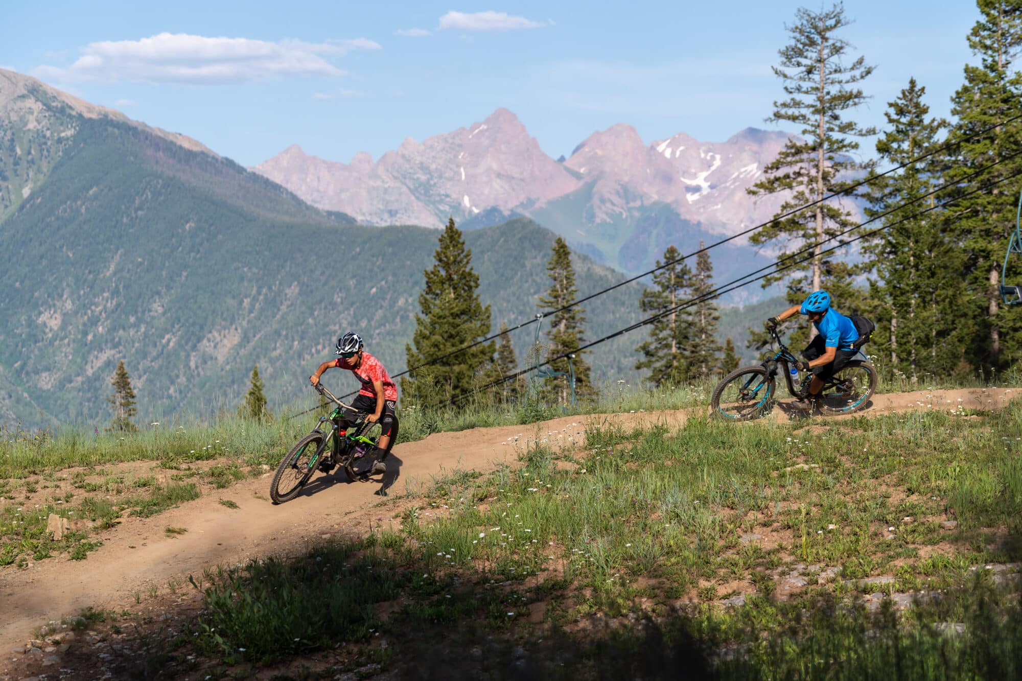 Mountain bikers attack a corner turn with the twilight mountains in the background