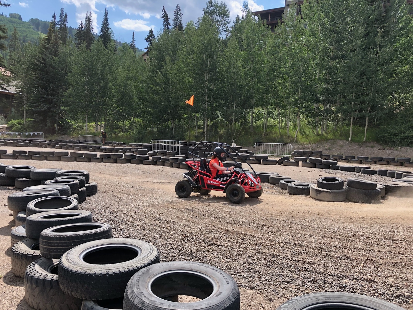 Female driving motorized go-kart hugs the inside tire barrier heading into a sharp left turn