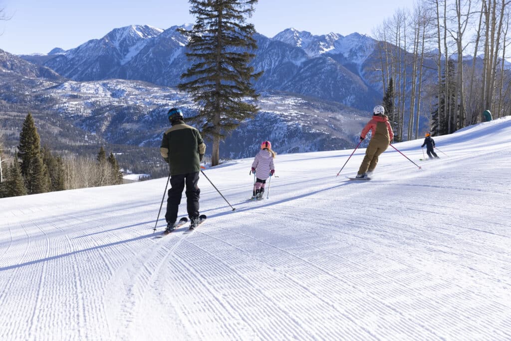 A family skis together on a groomer run