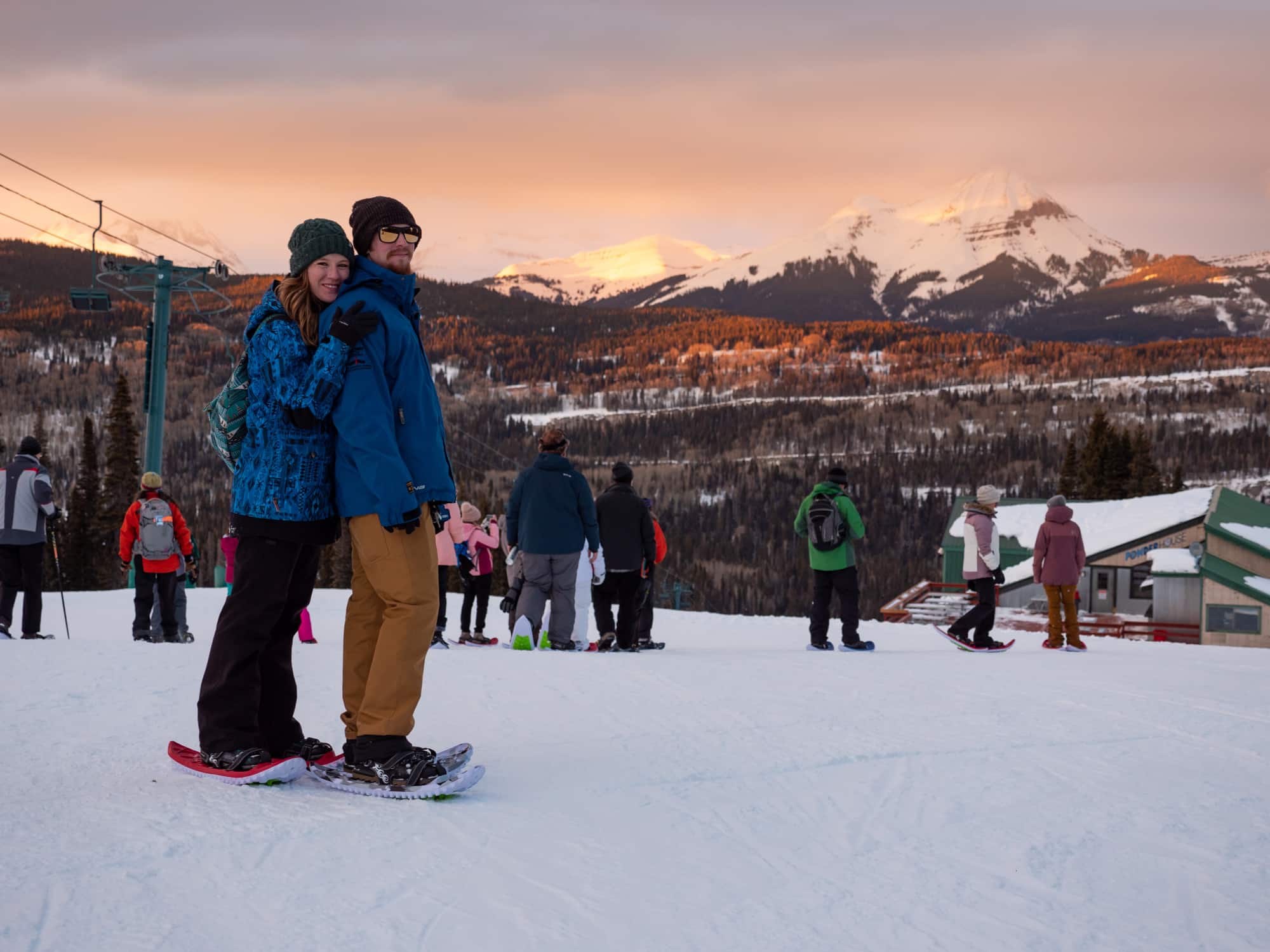 Young couple on snowshoe tour stops to take in the alluring sunset views