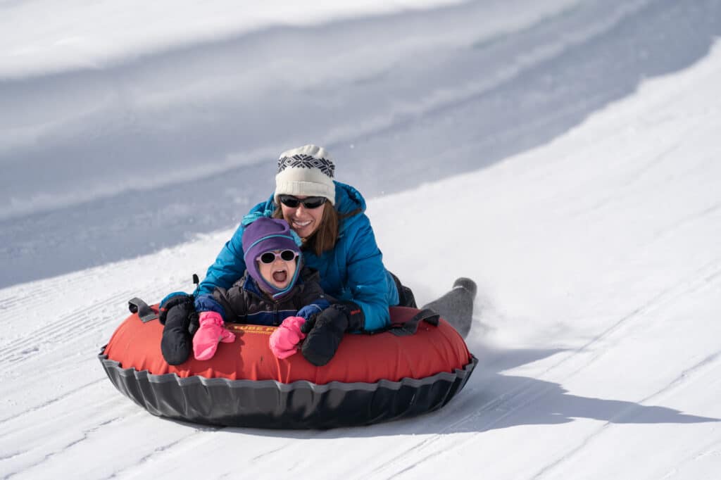 Mom and daughter sliding down the tubing track having the time of the lives as the approach the turn