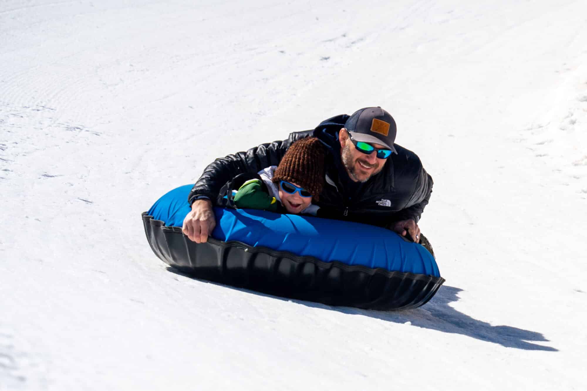 Father and son take on the banked turn at the tubing hill