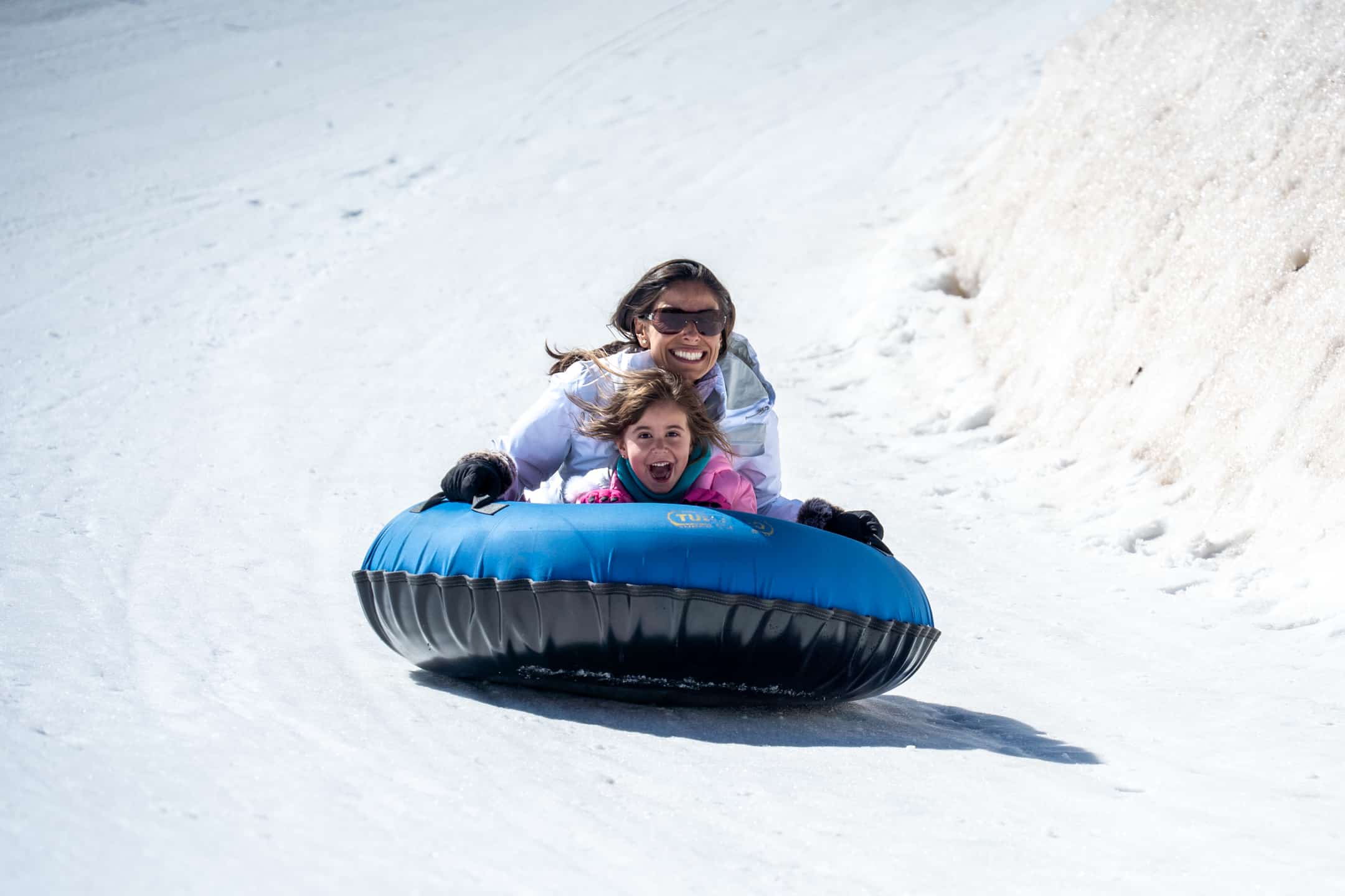 Pure enjoyment captured as mom and daughter glide down the tubing hill head first