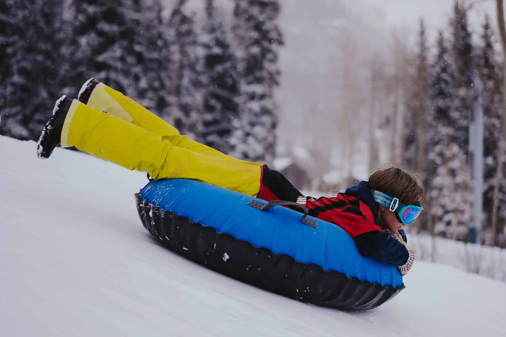 Young boy flying down the tubing hill