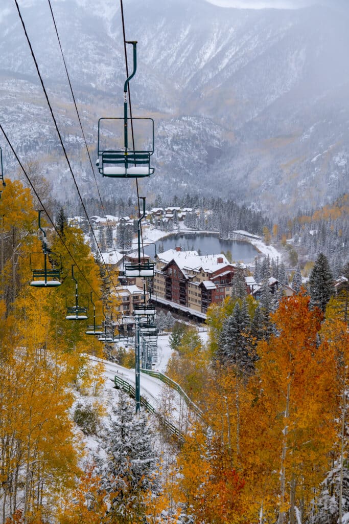 Lift four rising out of the base area covered in snow surrounding by fall aspens.