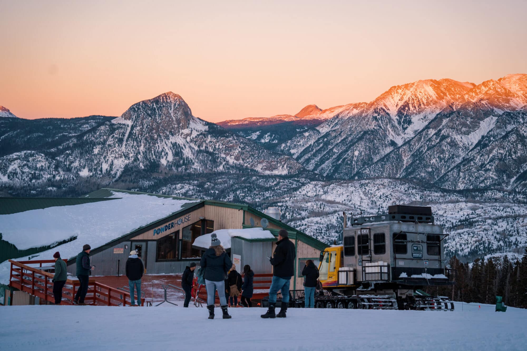 Guest unload the snowcat at Powderhouse during a beautiful sunset