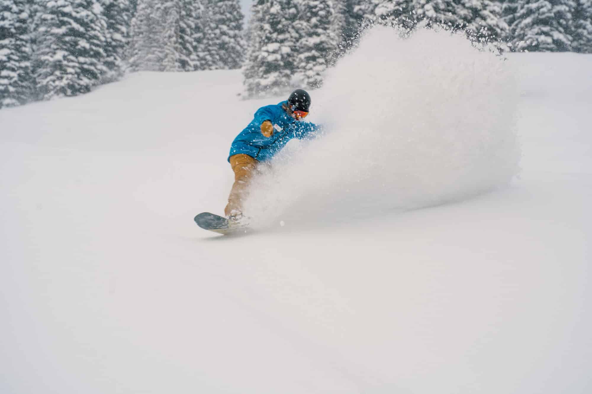 Purgatory employee turns through deep powder on a snowboard