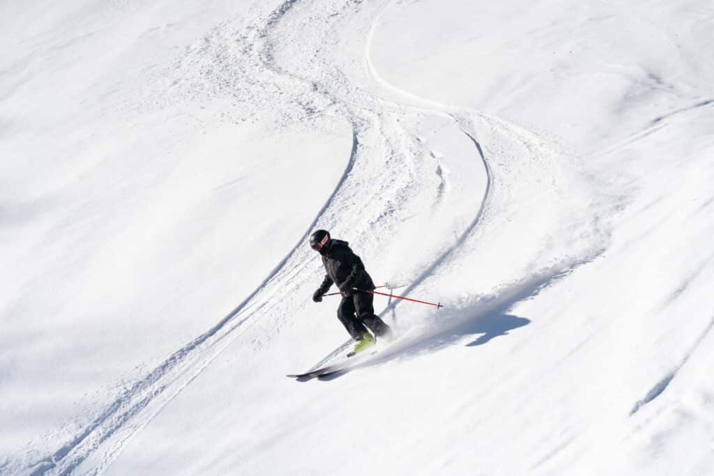 A skier makes turns down a fresh snow covered slope