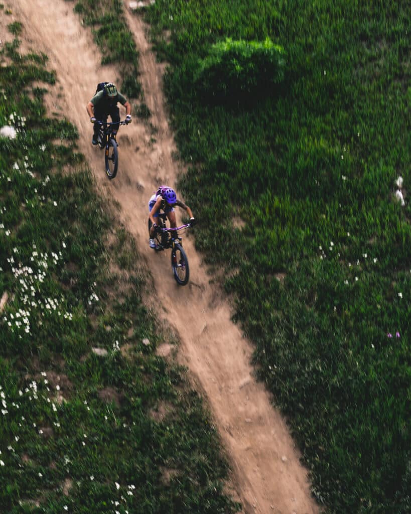 2 riders biking downhill on a foggy day