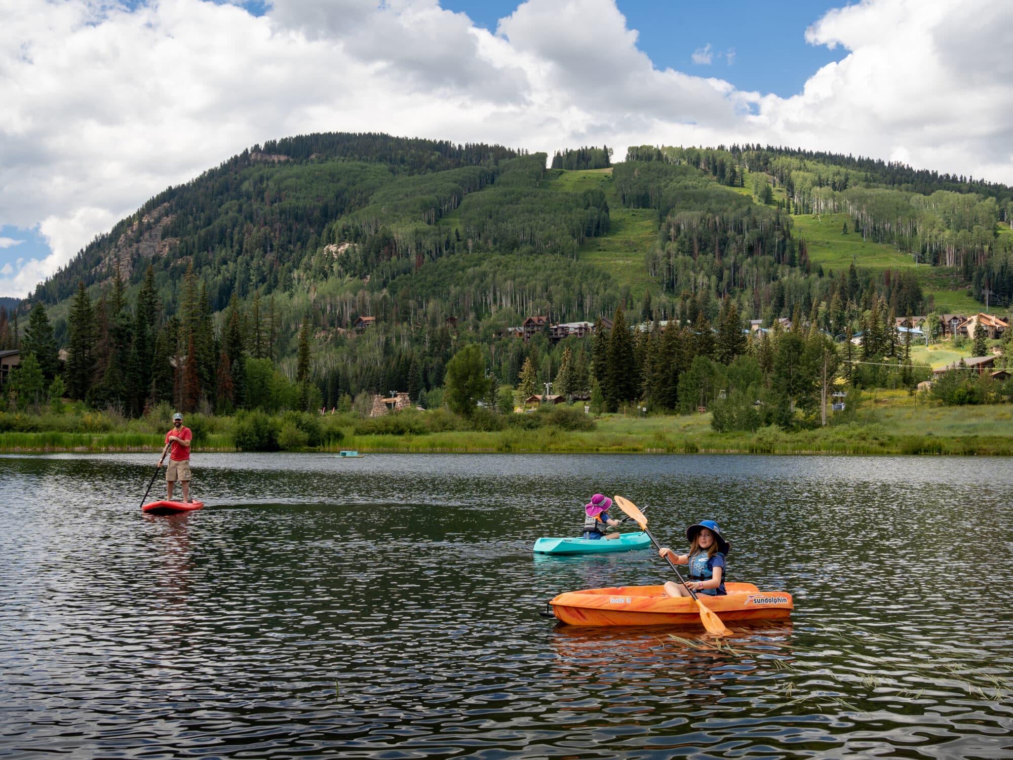 A family explores twilight lake on kayaks and paddleboard