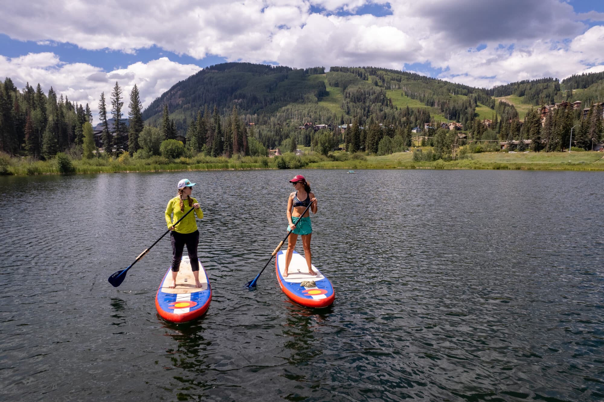 Two sisters paddle board across Twilight Lake on a summer day