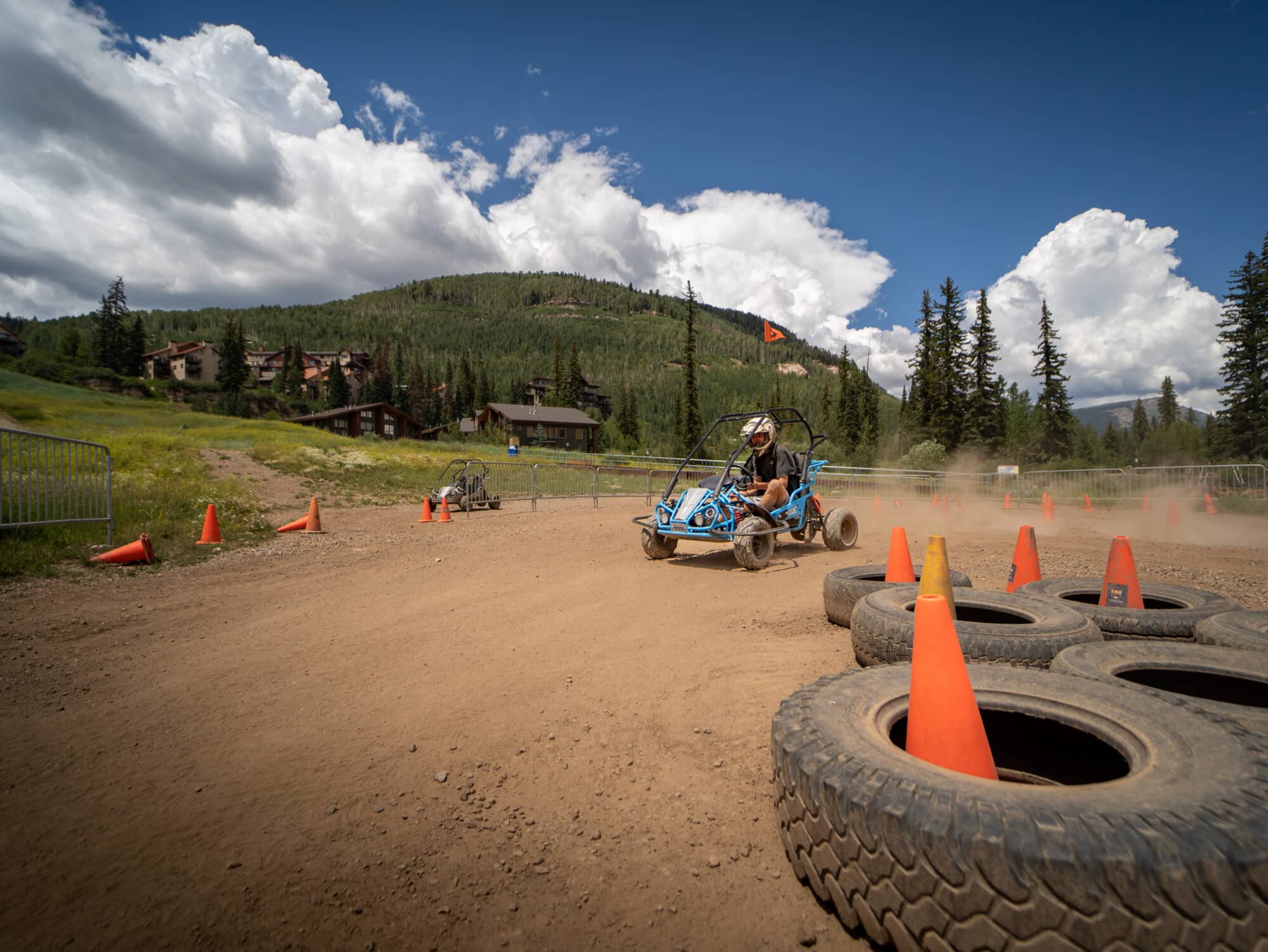 Driver of a blue go-kart rounds the corner on the kids off road track