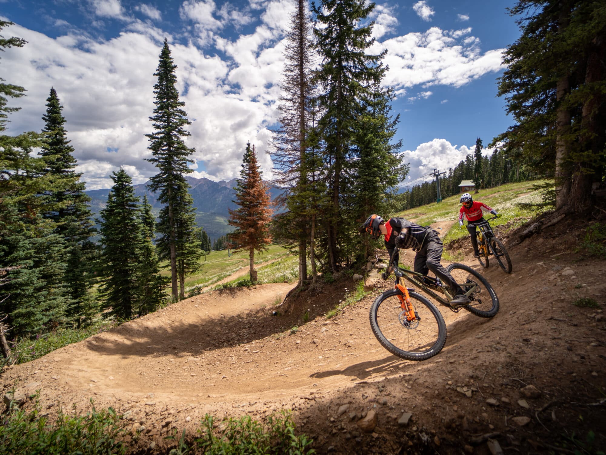 Bike instructor guides his student around a berm