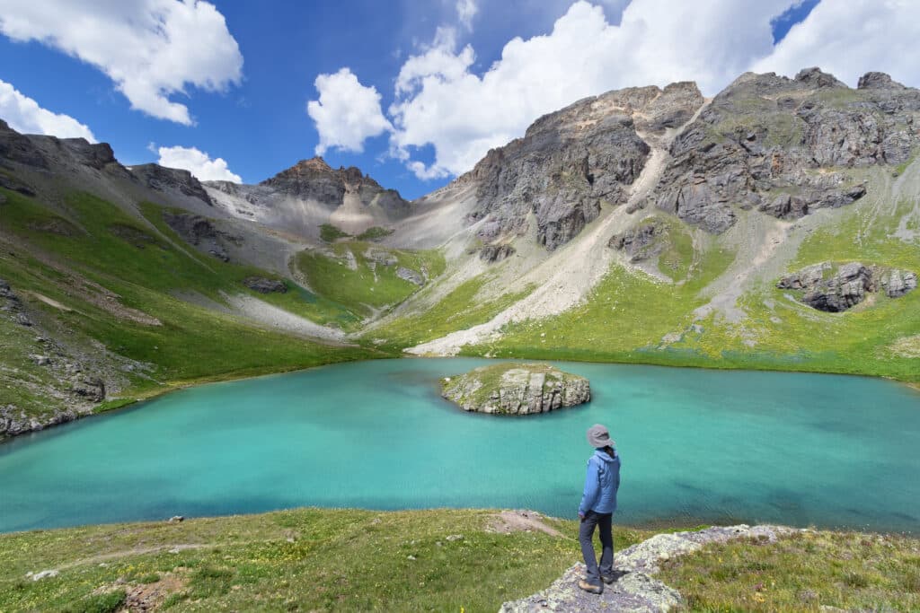 Female hiker looking over the beautiful Island Lake near Silverton, Colorado