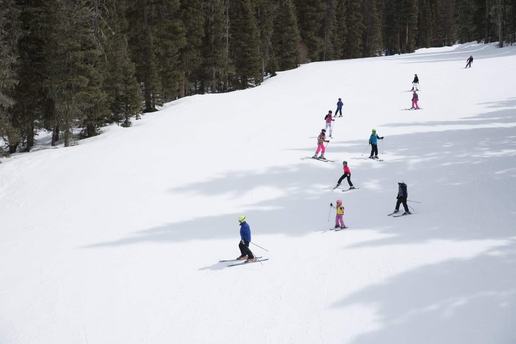 Ski instructor leads his group of kids down the mountain