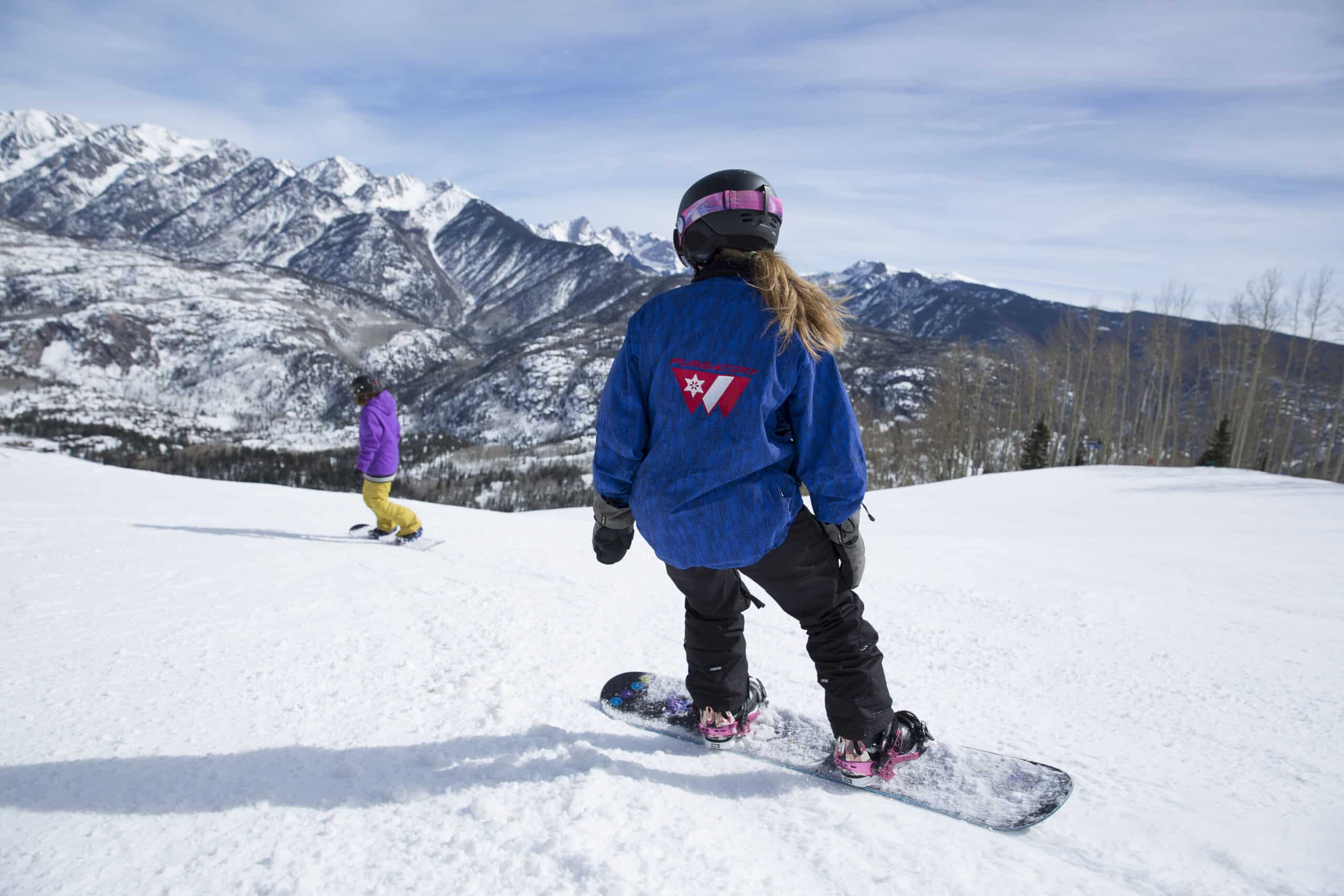 Snowboard instructor follows student down the mountain during a private lesson