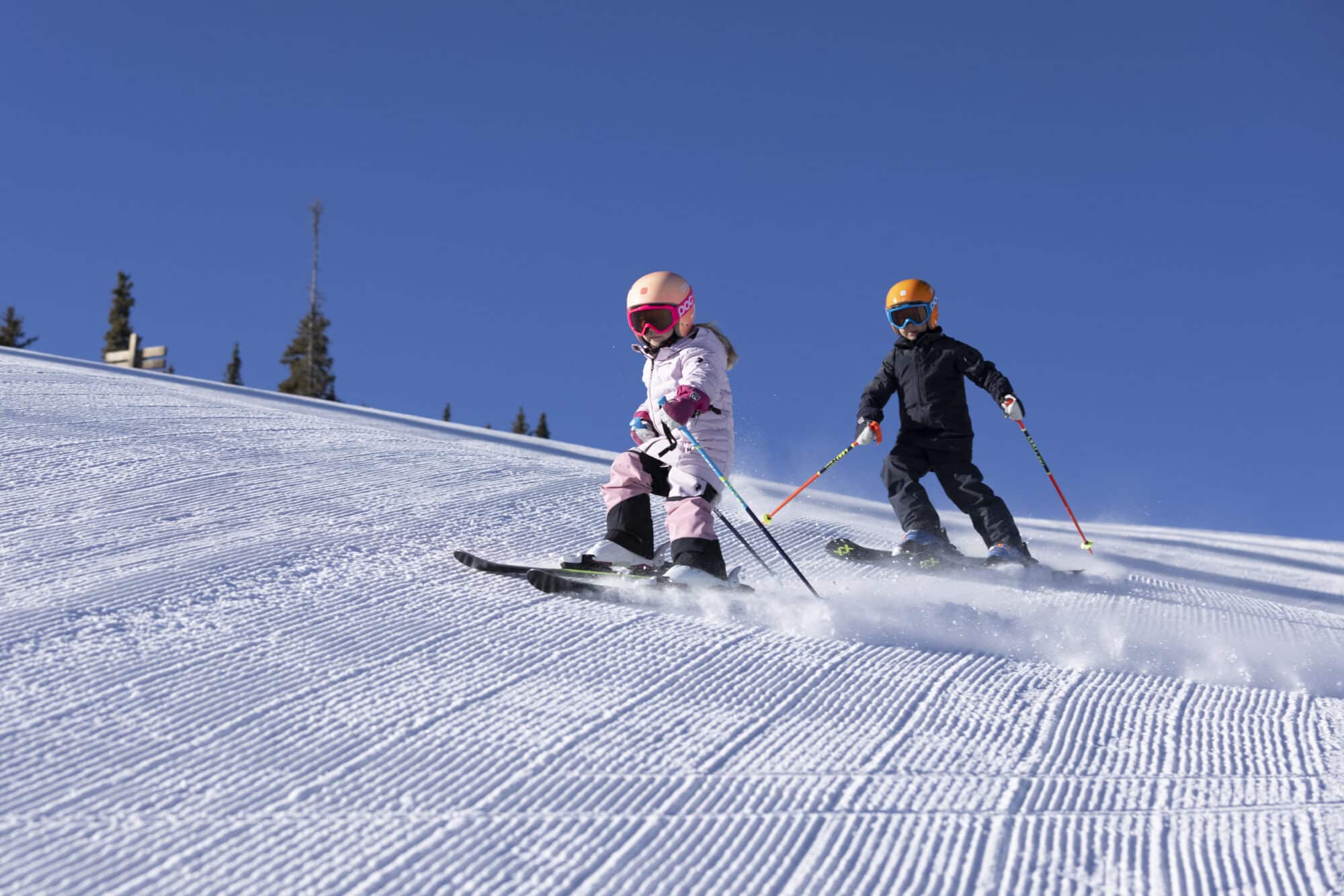 Brother and sister carve down the fresh morning corduroy