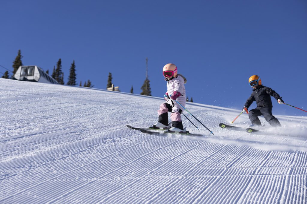 Young kids ski down fresh corduroy 