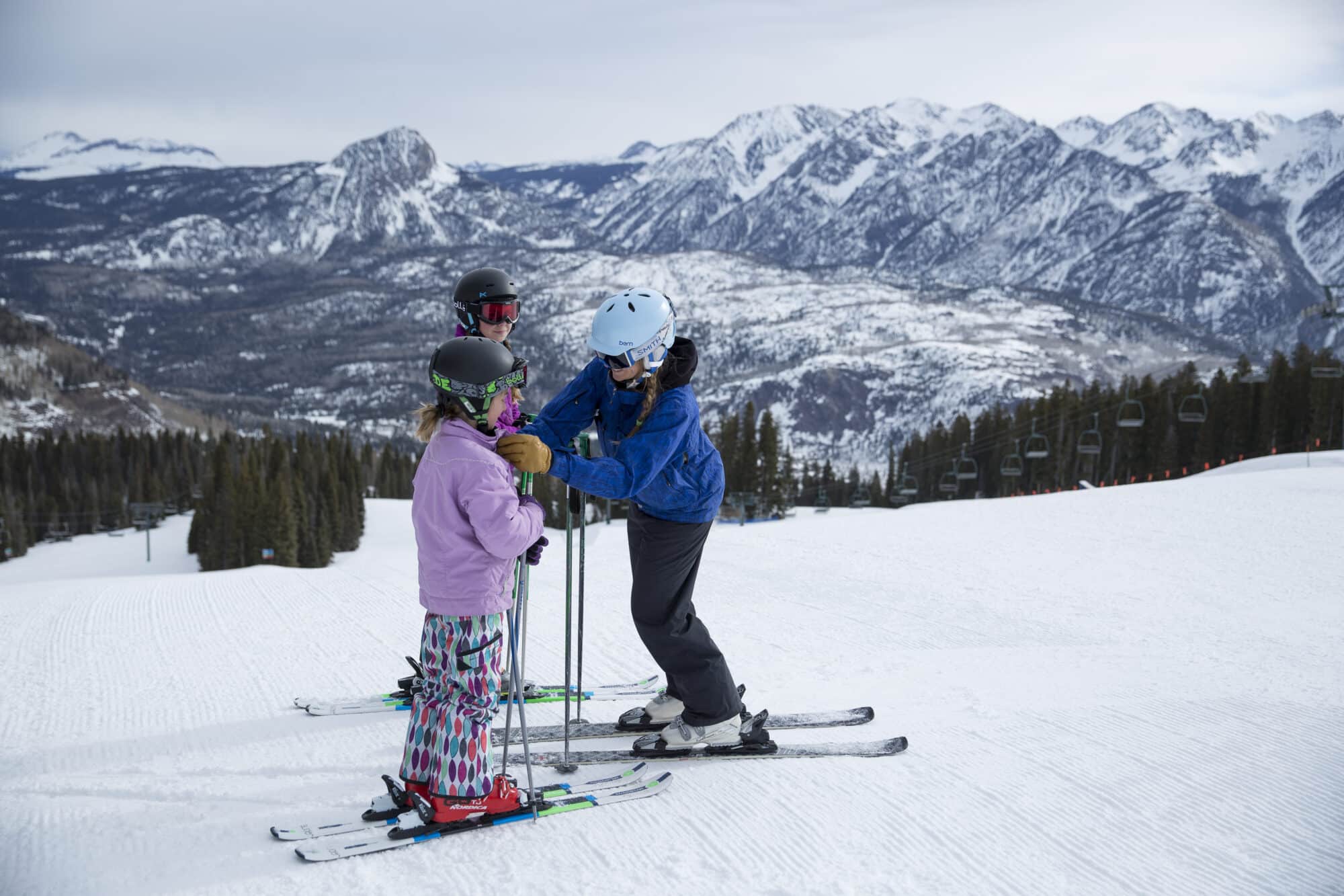 Instructor helps young student bundle up before heading down the mountain