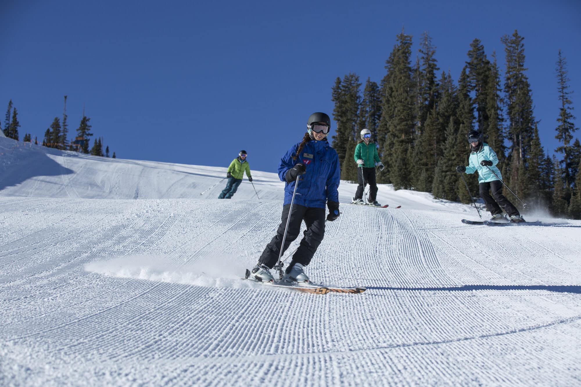 Ski instructor lead her group down fresh corduroy