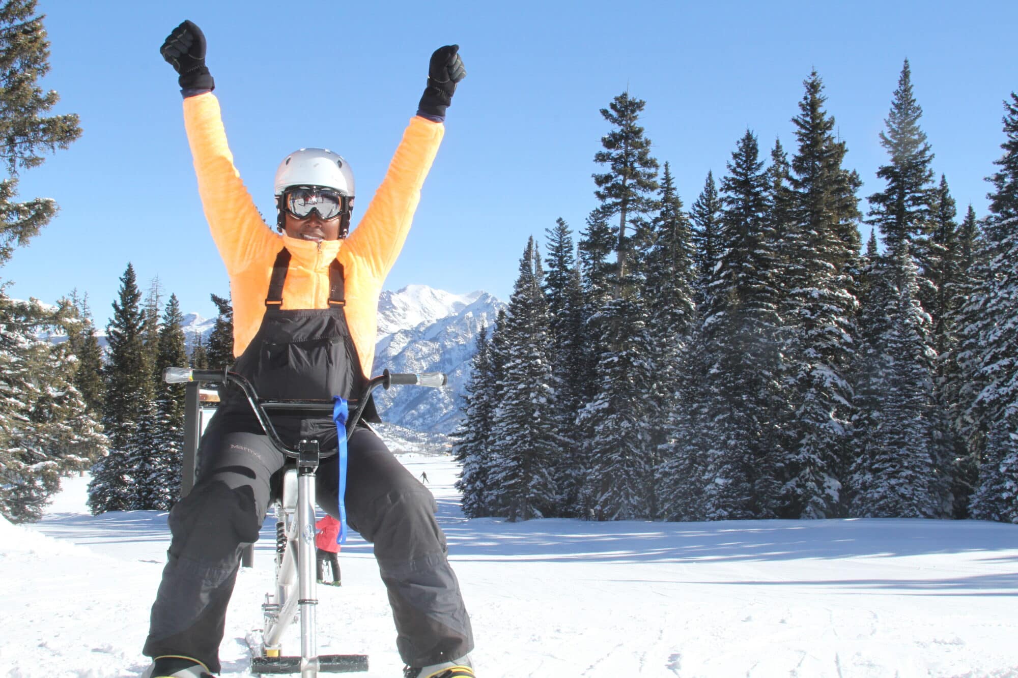 Adaptive ski bike rider celebrates on top of the mountain