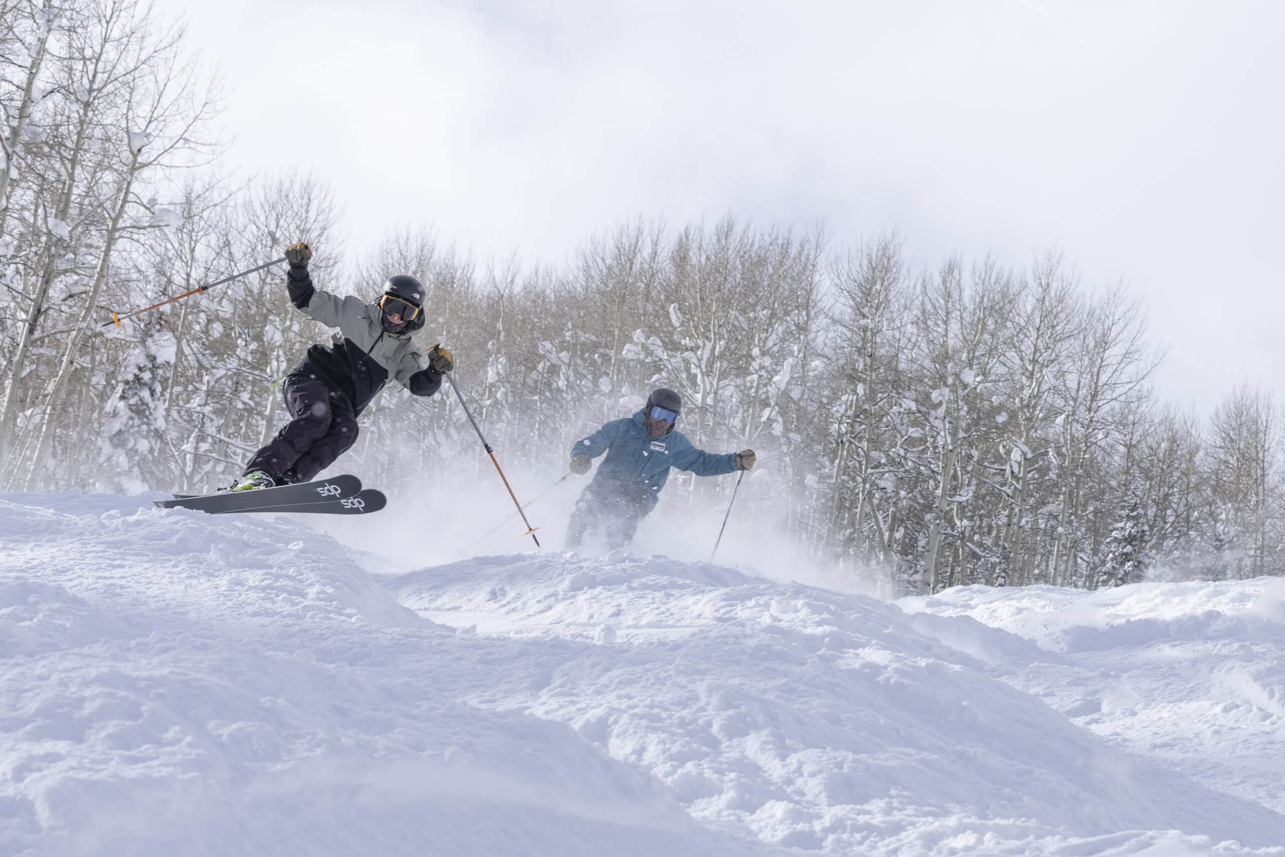Two skiers enjoy a moguls run