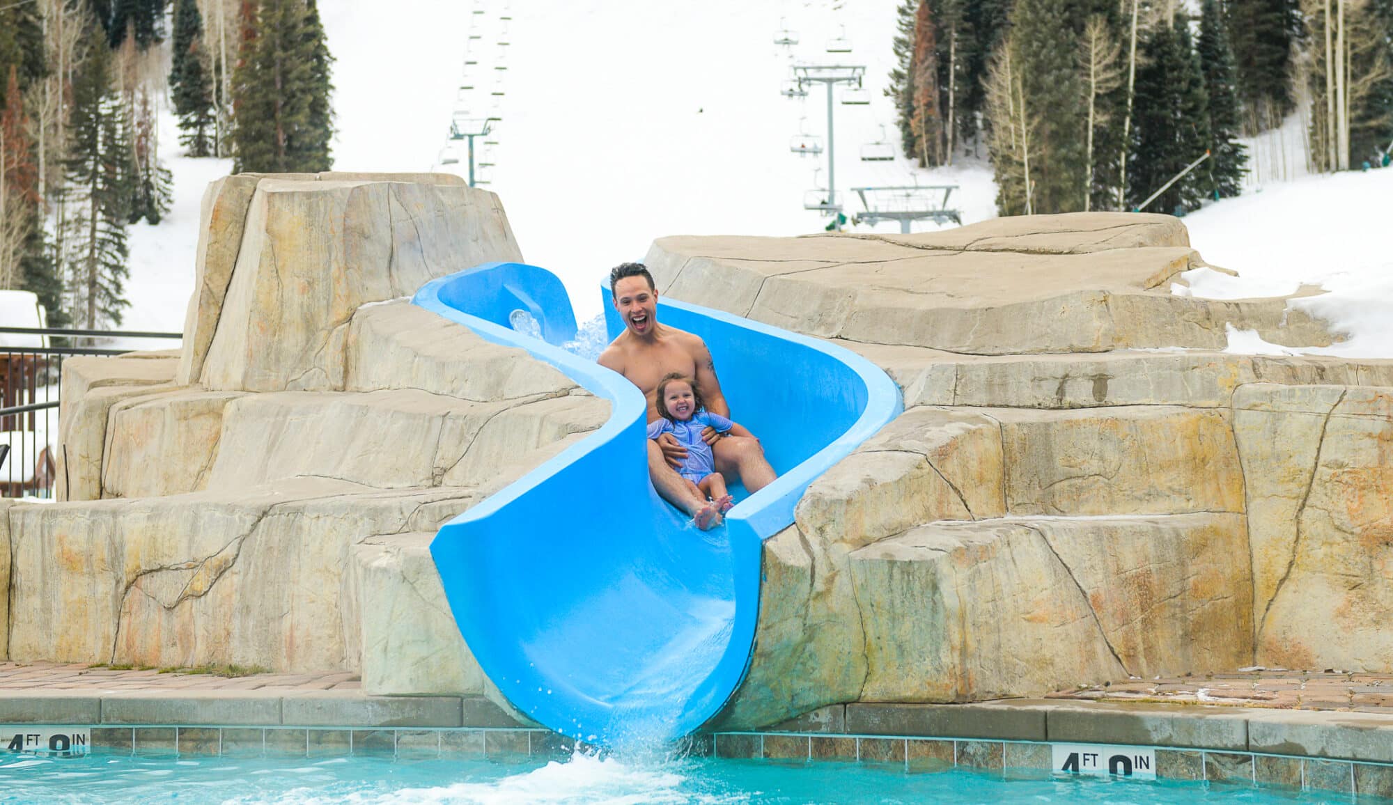 Family going down slide into pool