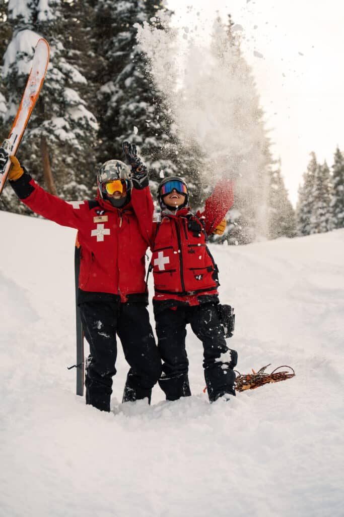 Two members of the ski patrol team toss snow into the air in celebration