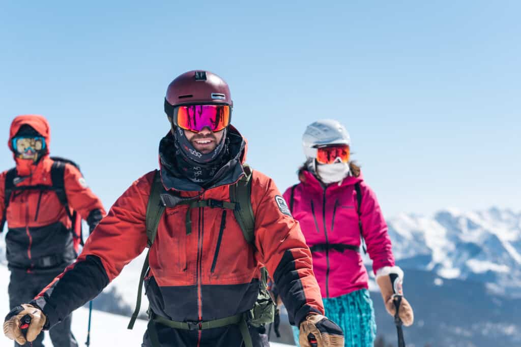 Snowcat skiing guide and group bask in the views at the top of Grayrock Peak
