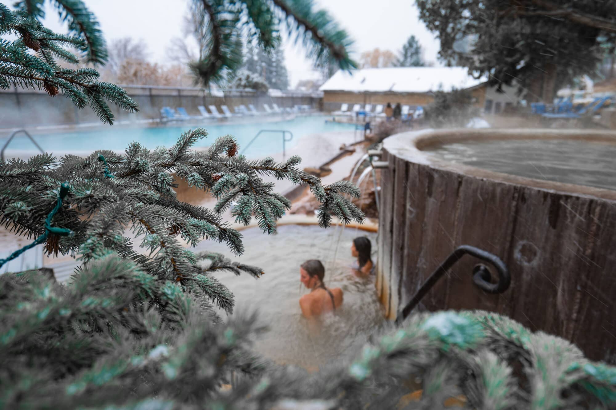 Two women soak in a warm pool as water cascades around them at Durango Hot Springs resort