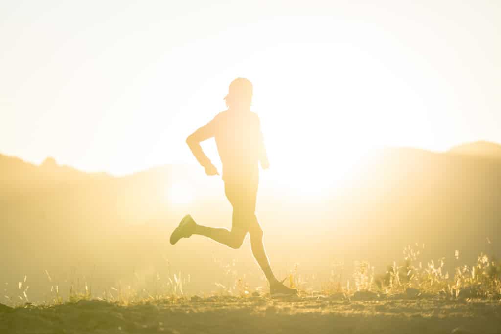 The autumn sun shines on a man running the Mountain Marmot