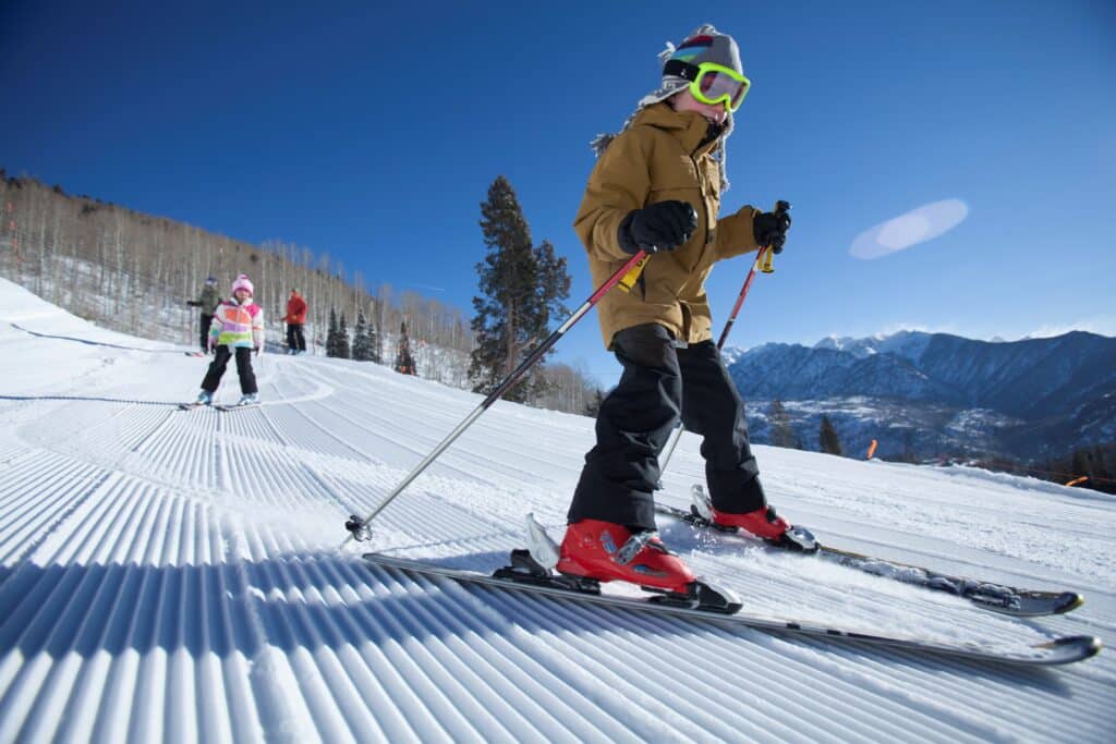 A boy smiles as he skis down a groomer