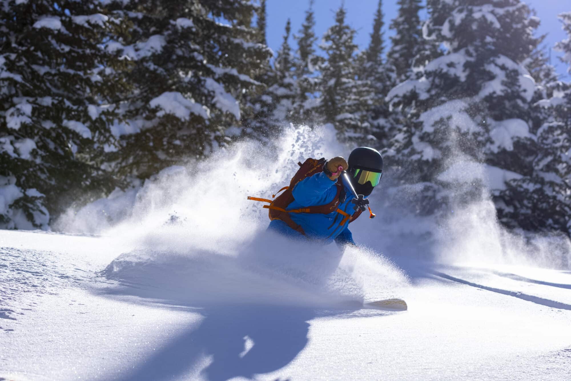 Skiers turns through waist deep powder on a snowcat skiing trip
