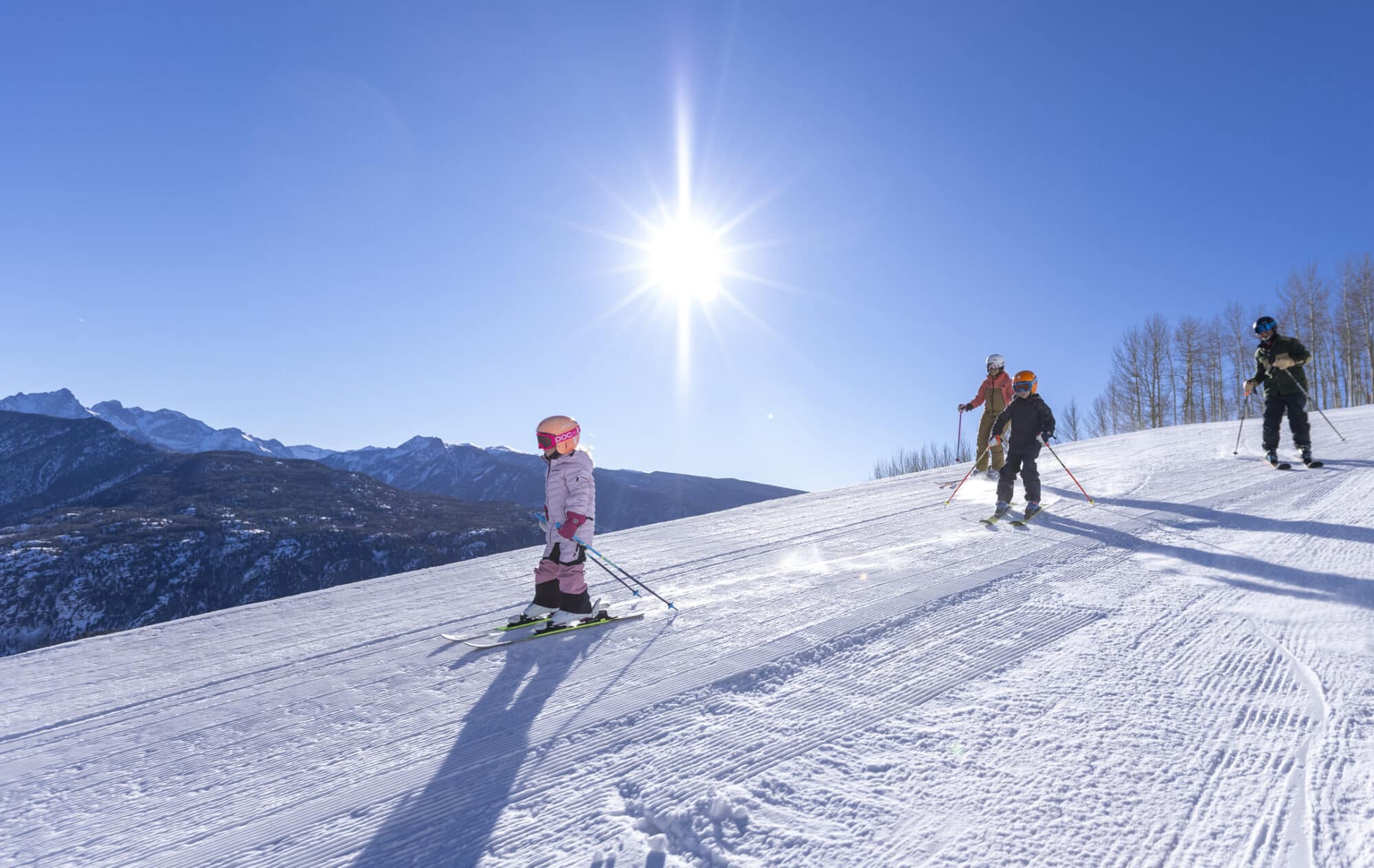 Family with young kids skies down a freshly groomed run