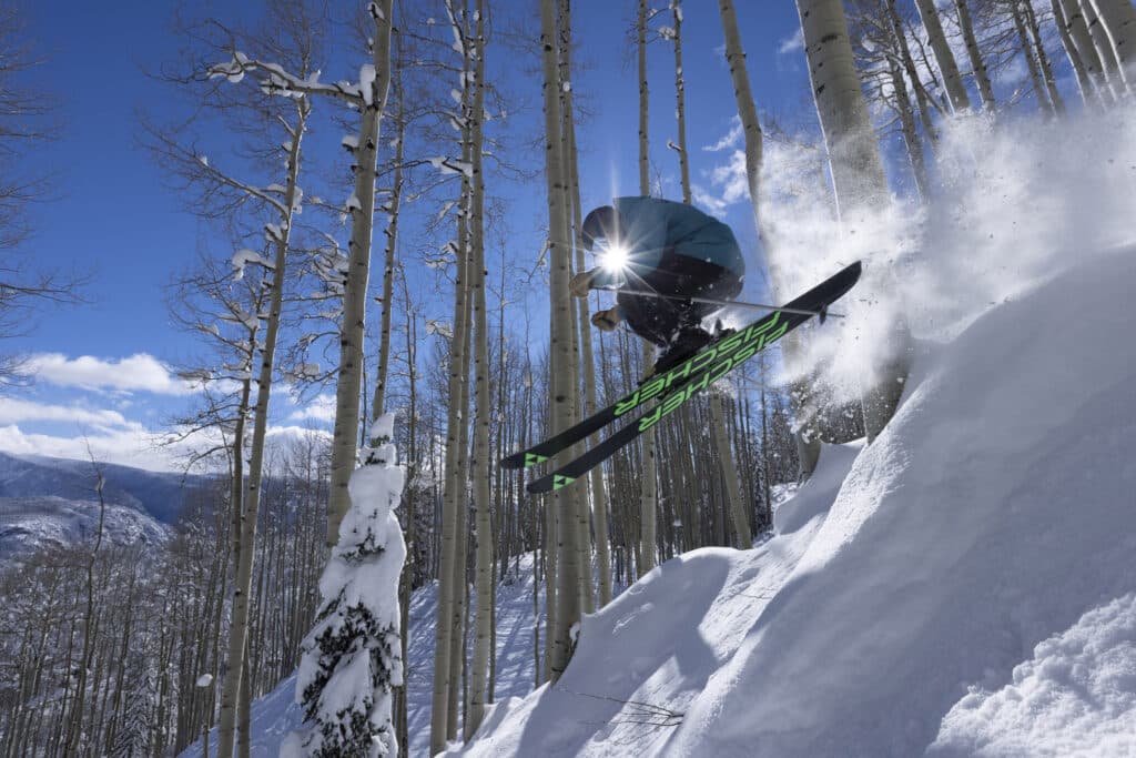 Skier catches air in the trees on a bluebird powder day