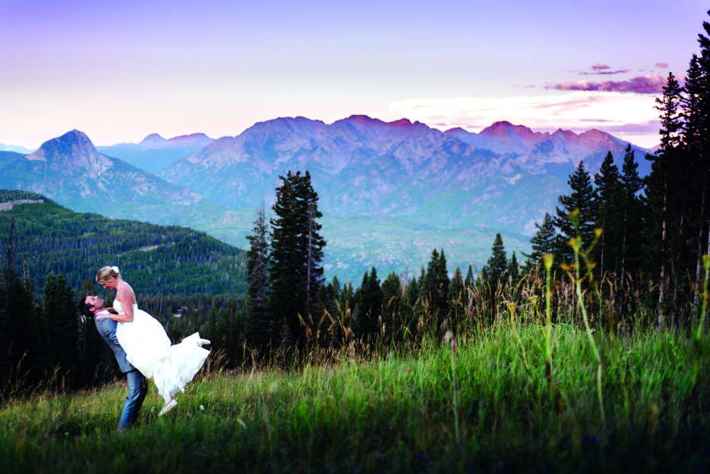 Newlyweds embrace each other during a purple mountain sunset