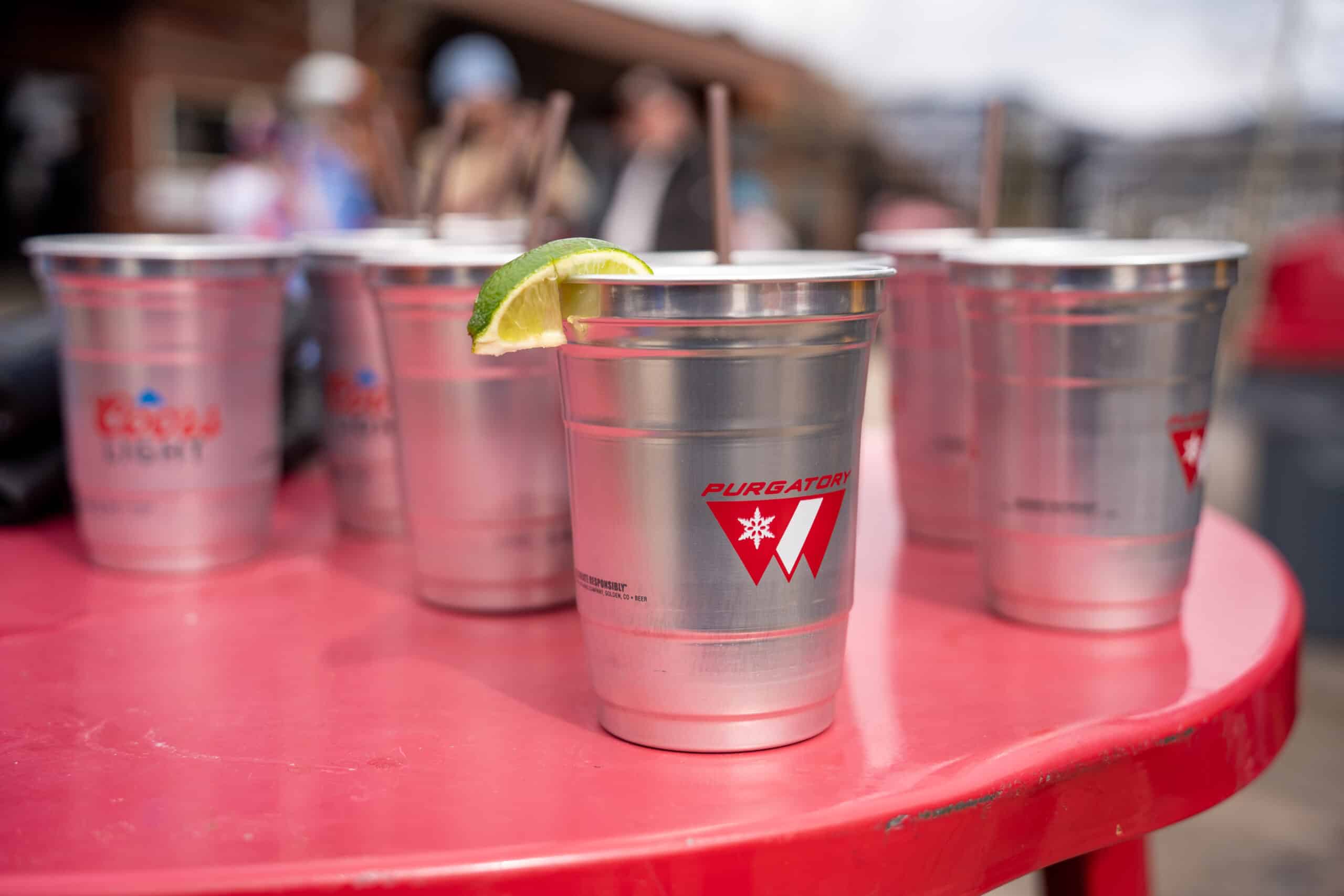Aluminum cups with lime garnish sit on a red table outside