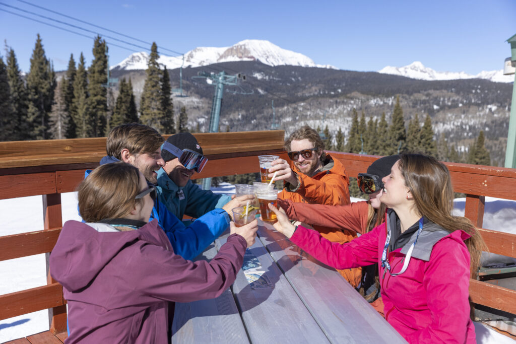 Friends cheers around a table on an outdoor patio in winter