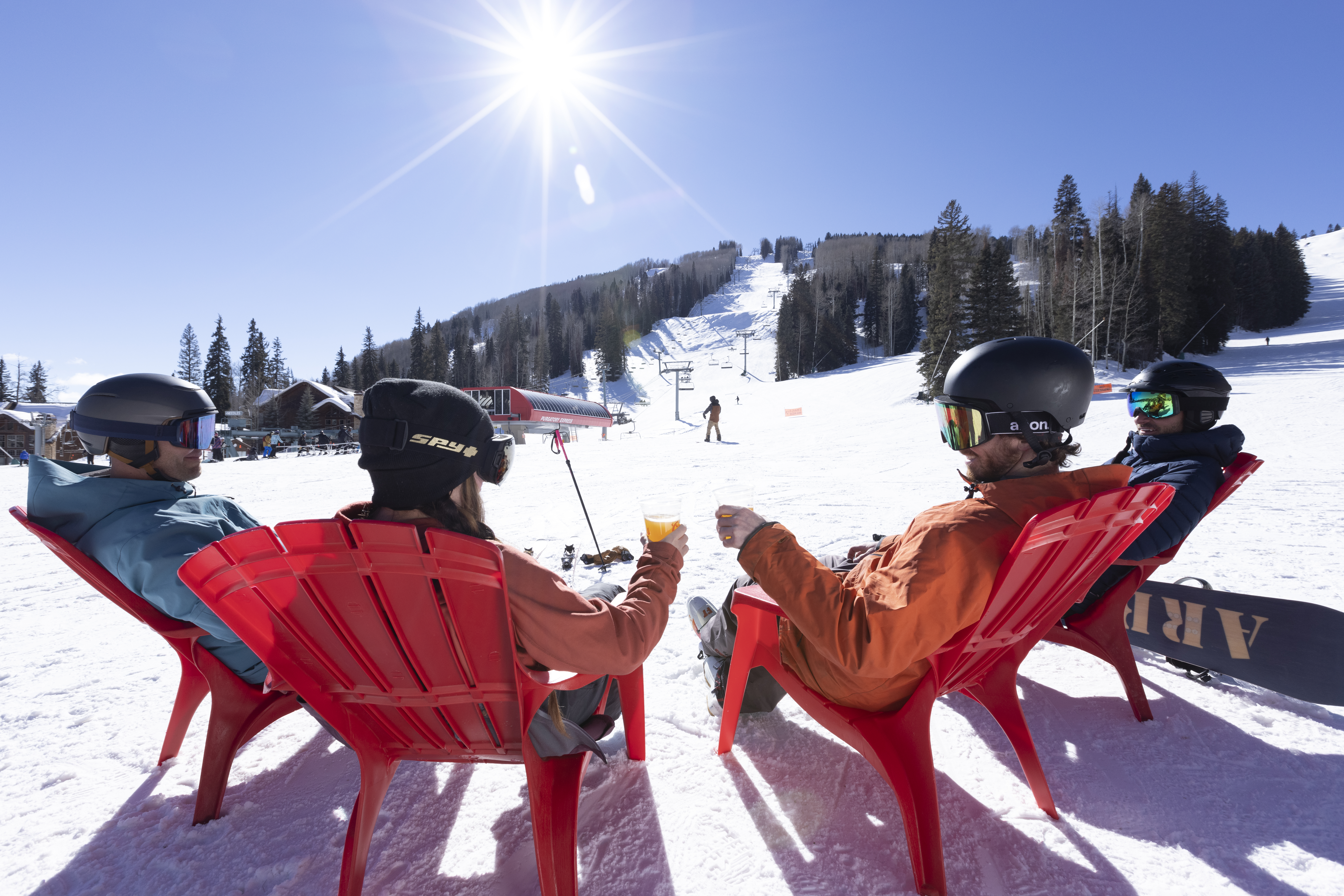 Friends cheers in red Adirondack chairs on the snowy beach area