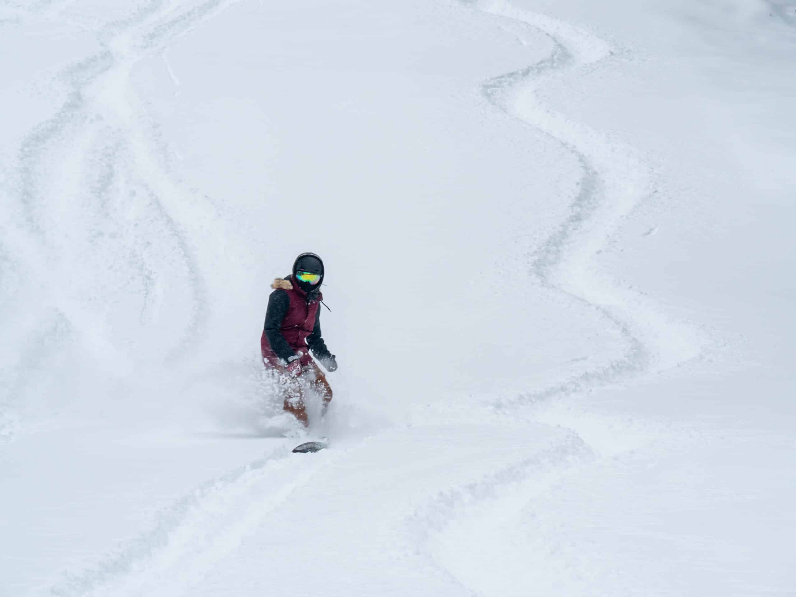 A Snowboarder leaves tracks in the powder on a snowy slope