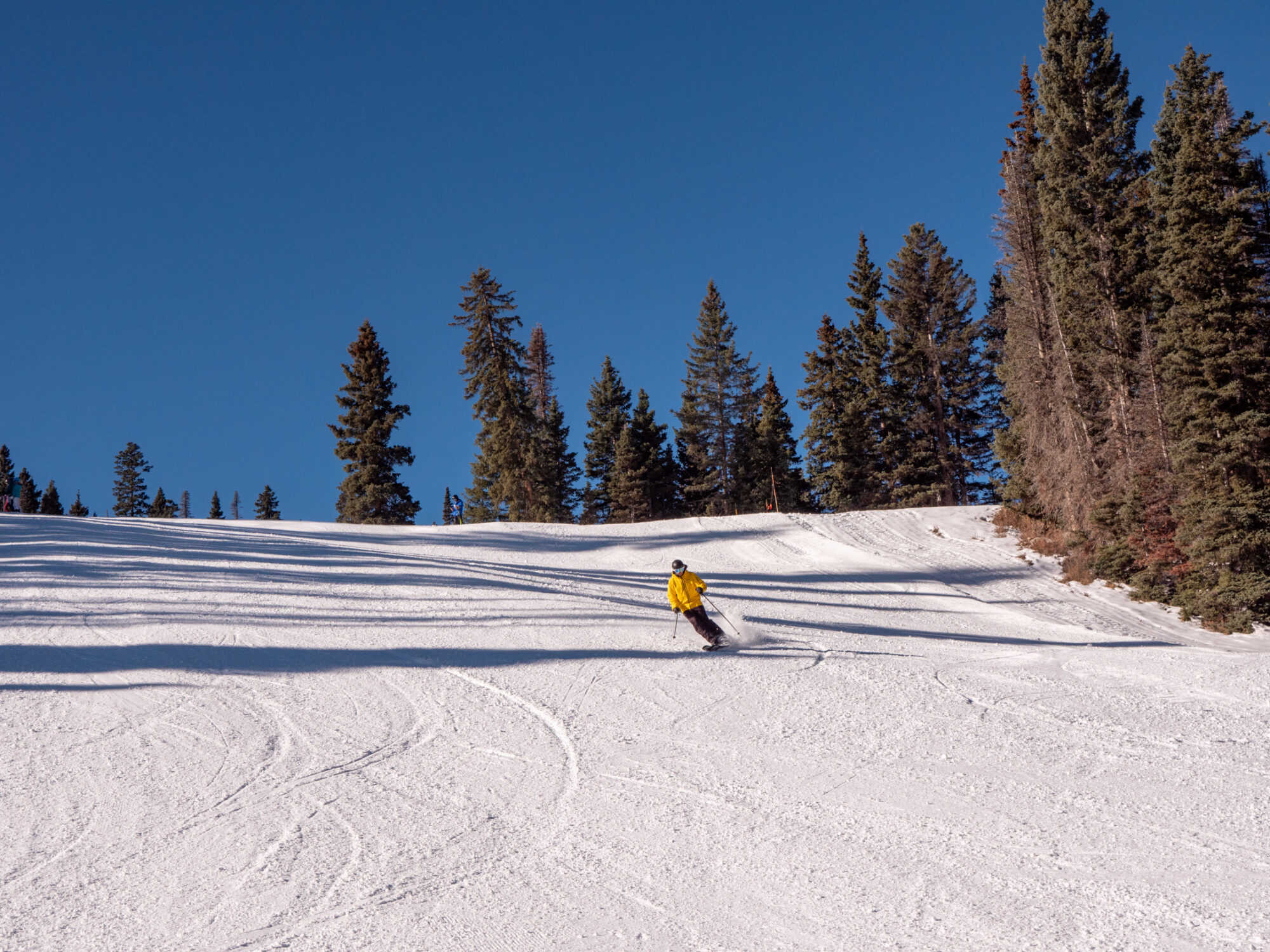 Skier skiing down slopes with blue sky